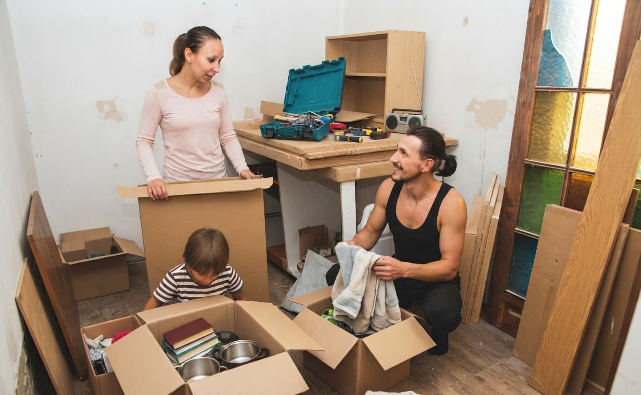 Couple sorting a toolbox and moving boxes while clearing a room