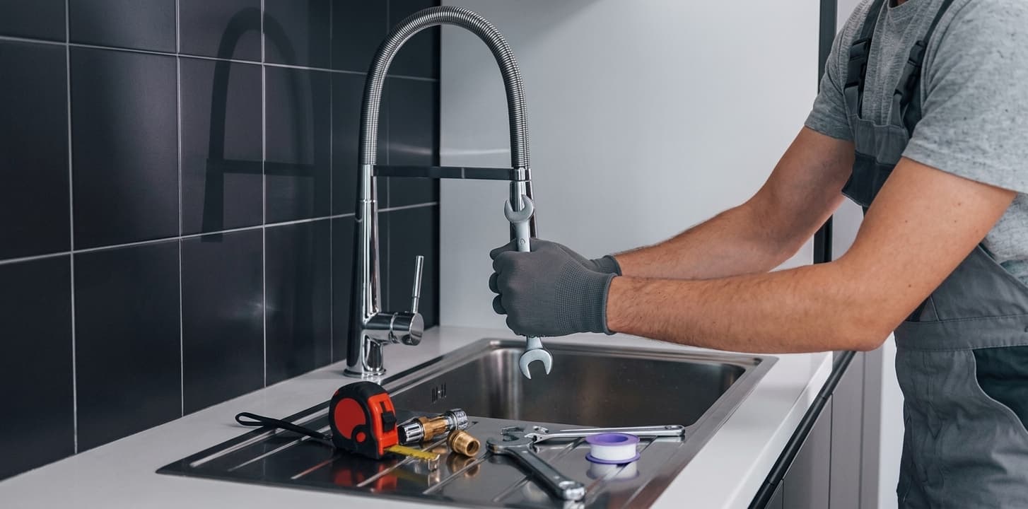 Plumber repairing a kitchen faucet